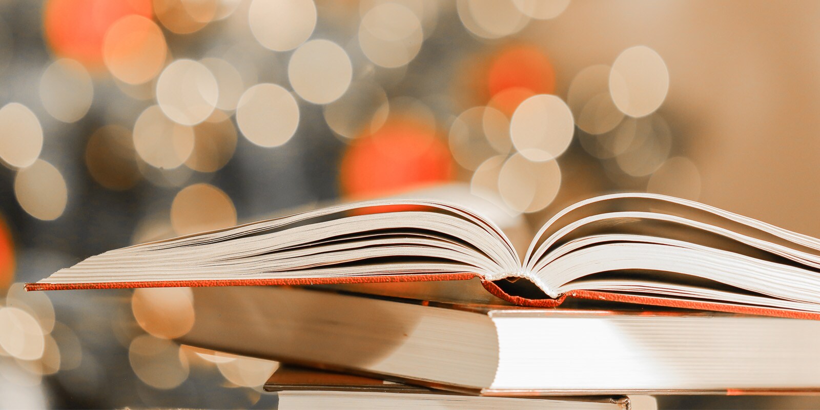 A stack of open books with twinkling lights in the background