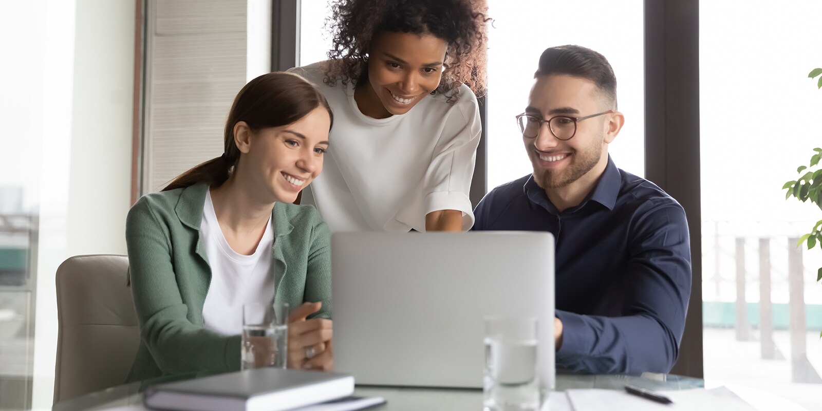 Three professional educators smiling while looking at a laptop computer