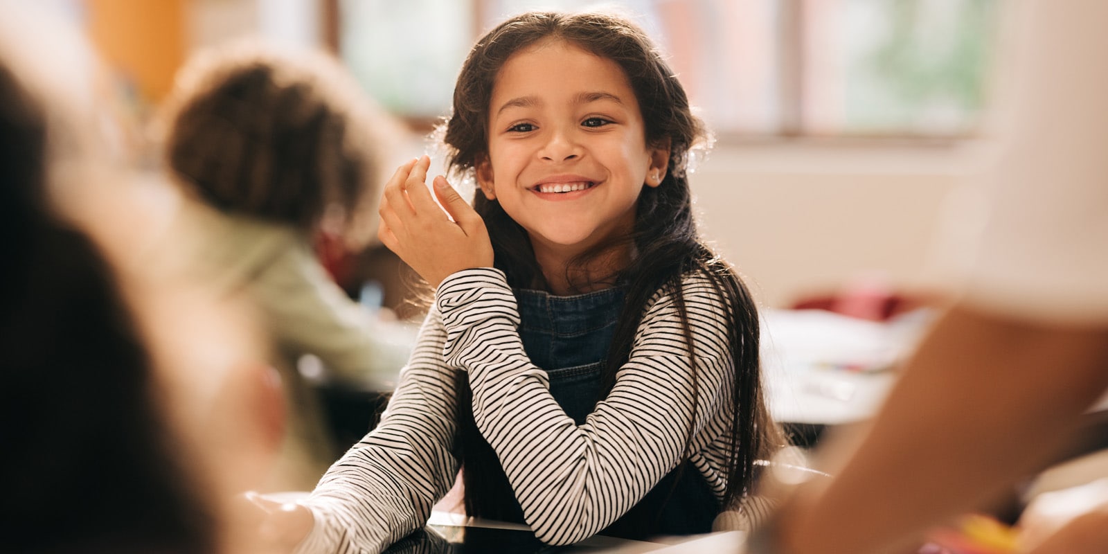 Student smiles in a classroom at her desk