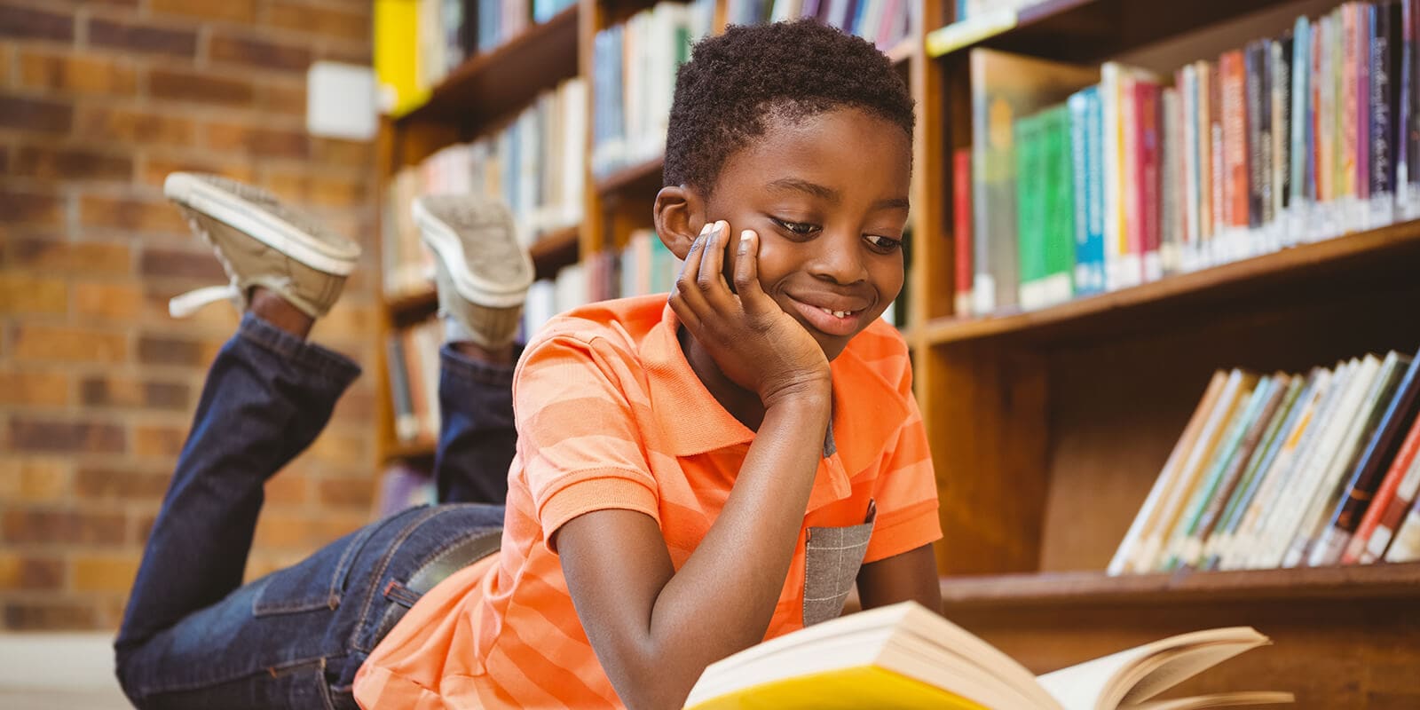Student smiles while reading a book in the library