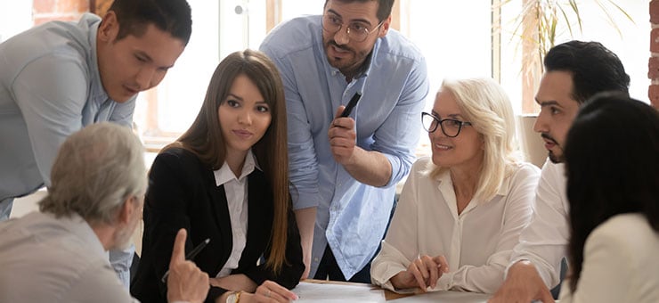 A group of colleagues having a meeting around a large desk.