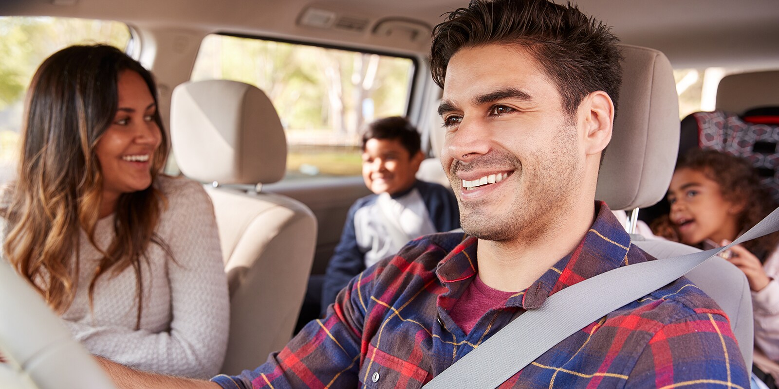 Two adults in front seats and two children in back seats of car.