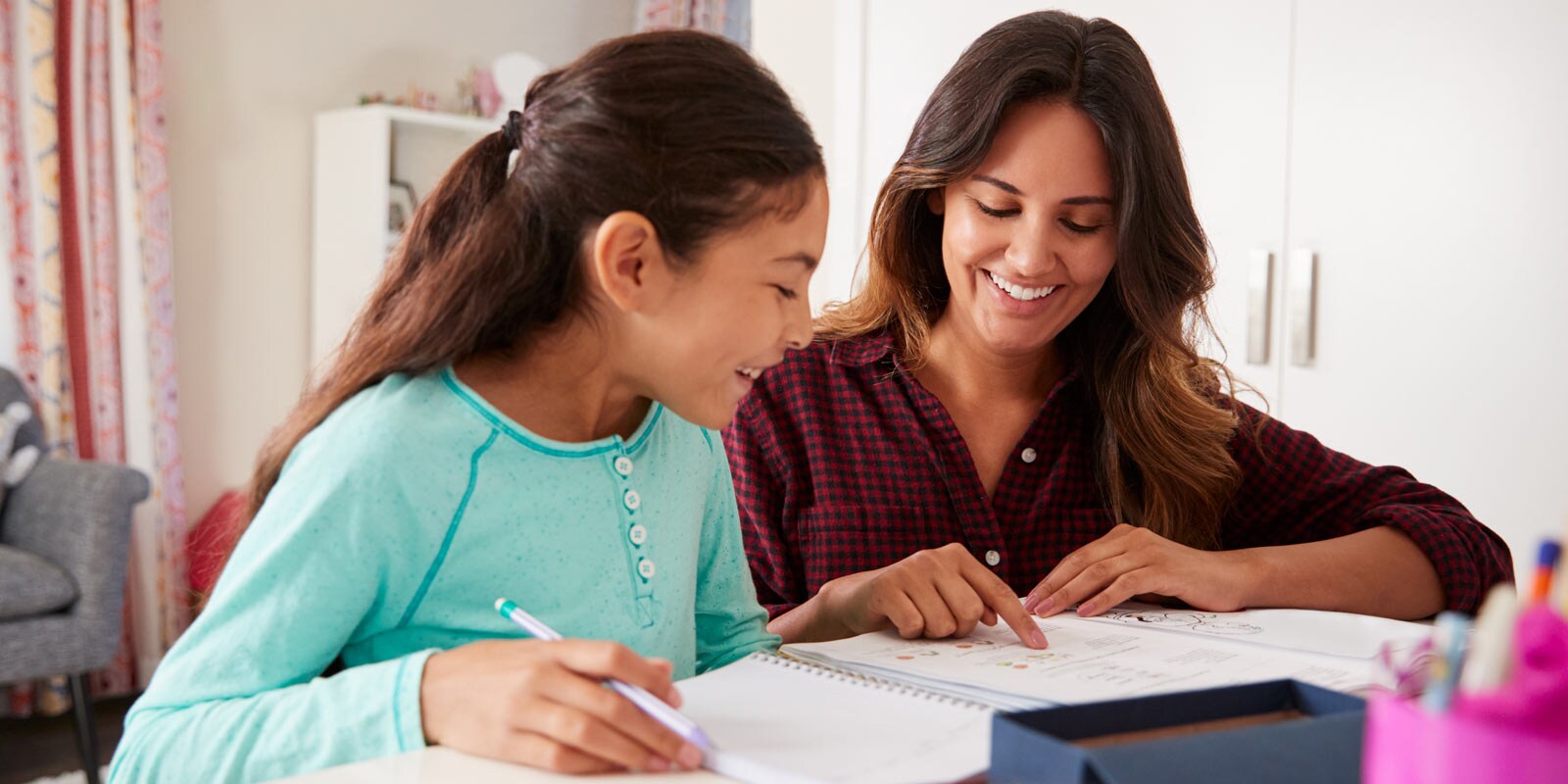 A smiling adult assisting a smiling child with school work