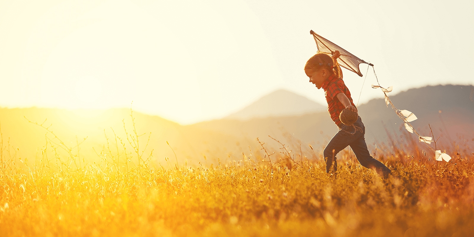 Child flying a kite at sunset. 