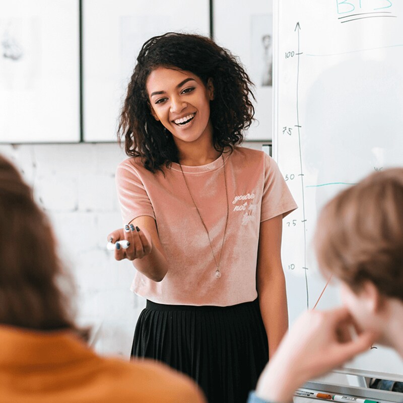 Female teacher in front of a classroom of high school students. 