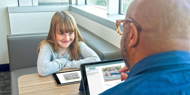 Child with tablet smiling at administrator with tablet